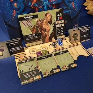 May include: A tabletop game with a wooden board and cards. The cards are green and brown with white text. The board has a wooden frame and a light brown surface. The cards are arranged in a circle around the board. The game is called "Dark"