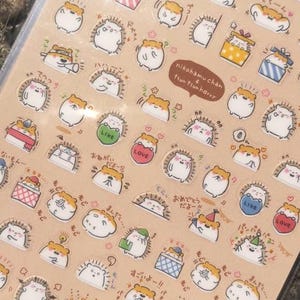 May include: A rectangular sticker sheet featuring numerous small, circular illustrations of cartoon hamsters and hedgehogs in various poses and expressions. The sheet includes a brown speech bubble with the text nikohamu chan & tsun tsun harry.