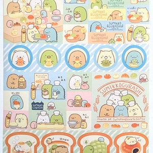 May include: A sheet of Sumikkogurashi stickers with cartoon characters in chef hats and food-themed illustrations. The stickers feature bears, penguins, and other creatures, with Japanese text. Measurements in cm.