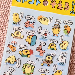 May include: Sheet of colorful cartoon stickers featuring various characters, including yellow chicks and other creatures. The stickers have speech bubbles with Japanese text and are on a light blue background.