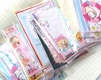 Puede incluir: Una pila de hojas de papel de carta variadas en un paquete de plástico transparente, con varias ilustraciones de dibujos animados coloridos, patrones florales y el texto Rilakkuma y Cutie Princess en las páginas.