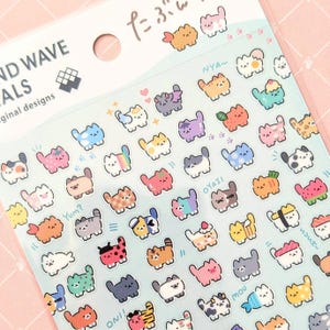 May include: A sticker sheet featuring numerous small, colourful cartoon cat illustrations in various themes, including food, animals, and patterns. The top header includes the text "AND WAVE" and "ALS" along with Japanese characters.