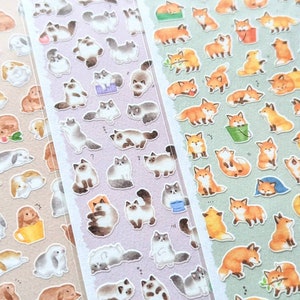 May include: Three sheets of stickers featuring adorable illustrations of cats, foxes, and bunnies. The stickers are printed on white paper with a light pink, light blue, and light brown background.