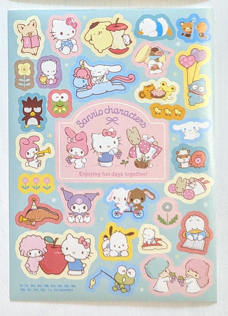 May include: A sheet of colourful Sanrio character stickers on a light blue background. The stickers feature various characters like Hello Kitty, My Melody, and others, with the text "Sanrio characters" and "Enjoying fun days together!".