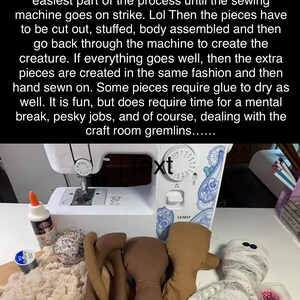 May include: A white Brother LX3817 sewing machine sits behind craft supplies including a bottle of glue, a spool of thread, a pin cushion, fabric scraps, three brown fabric doll bodies, and a finished mummy doll wrapped in white gauze.