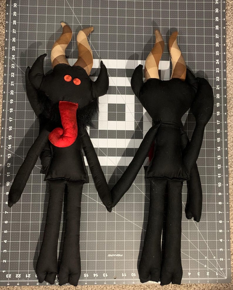 Two black fabric Krampus characters with long limbs and horns.  One is facing forward the other showing the backside.