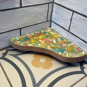 May include: A colorful, abstract, wooden corner shelf with a wavy edge. The shelf is painted with swirls of yellow, green, blue, orange, and pink.
