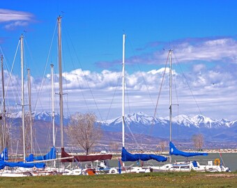 Sailboat on water, fine art photograph, color photo, landscape photography, snow capped mountains, lake, clouds, blue sky, trees, colorful