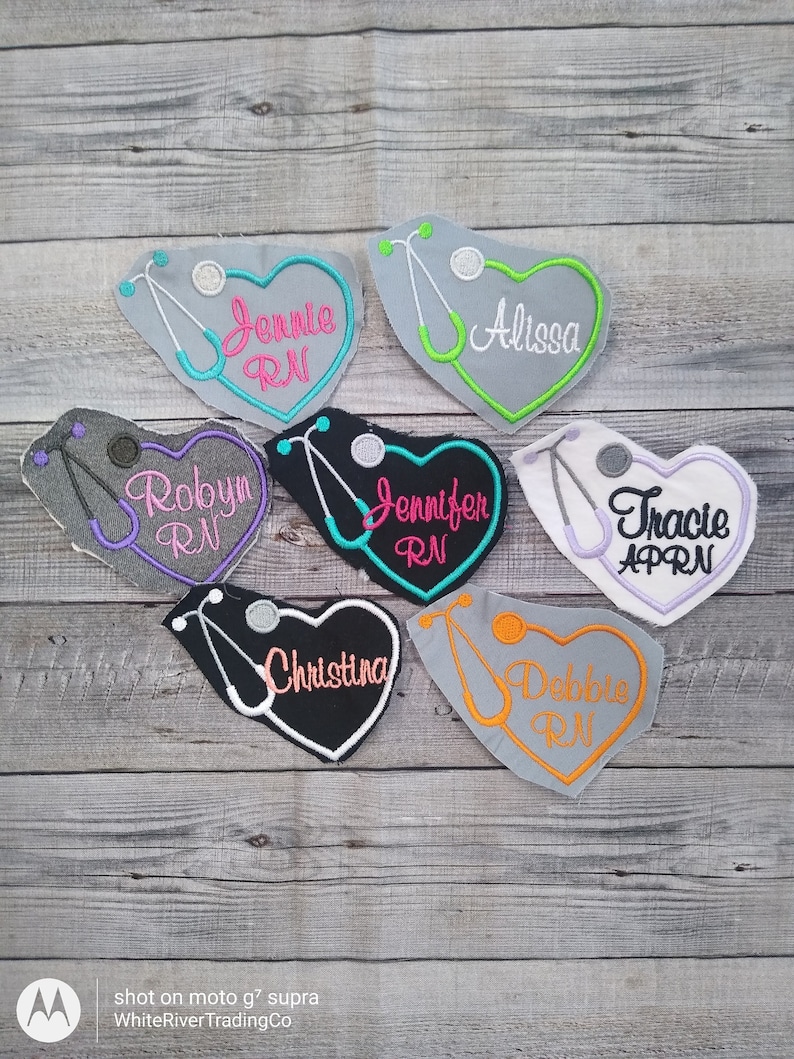 May include: Six heart-shaped embroidered patches with a stethoscope design and names, including 'Jennie RN', 'Robyn RN', 'Jennifer RN', 'Alissa', 'Tracie APRN', and 'Debbie RN'.