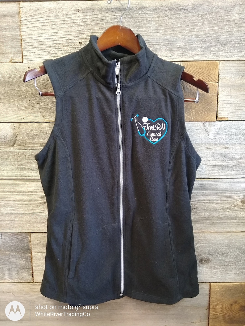May include: Black fleece vest with a zipper closure and a blue embroidered heart with the text "Toni RN Critical Care".