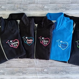 May include: Five black fleece jackets with a zipper closure and a stethoscope and heart design embroidered on the left chest. The embroidery includes the names "Brittany RN", "Jennifer RN", "Grace RN", "Jennifer RN", and "Angie EMT RN".