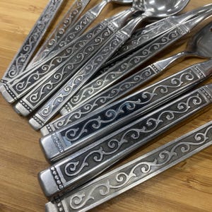 May include: A set of silver flatware with ornate black and silver designs on the handles.