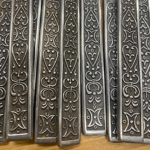 May include: A set of silver-colored flatware with intricate floral patterns etched into the handles.