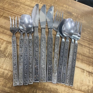 Puede incluir: Un juego de diez piezas de cubiertos plateados con diseños florales. El juego incluye tenedores, cucharas y cuchillos.