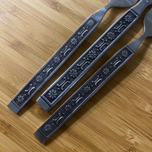 May include: Three silver forks with a floral pattern etched into the handles.