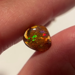 May include: A brown, green, and red opal gemstone with a rough, natural finish.
