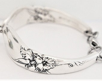 May include: A silver bracelet made from a vintage spoon with a floral design and a single green bead charm.