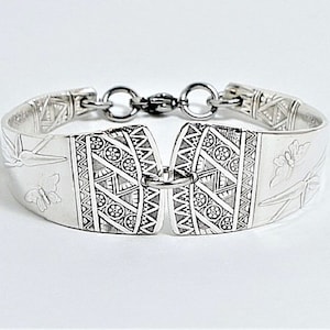 May include: A silver bracelet made from a repurposed spoon with a geometric pattern and butterfly design.