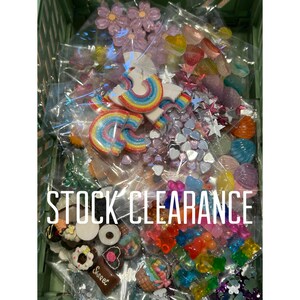 May include: A selection of colourful craft supplies, including rainbow-shaped embellishments, flowers, hearts, and other decorative pieces. The text "STOCK CLEARANCE" is displayed in white block letters.