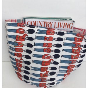 May include: A white tote bag with a red, white, and blue pattern of cartoon guardsmen. The bag is filled with a magazine titled "Country Living" with the text "Food, Travel, Health".