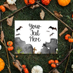 Puede incluir: Una tarjeta blanca con el texto "Your Text Here" y una ilustraci&oacute;n de acuarela de un cementerio con l&aacute;pidas, una cruz y murci&eacute;lagos. La tarjeta est&aacute; rodeada de calabazas, calabacines y ramas sobre un fondo de hierba verde.