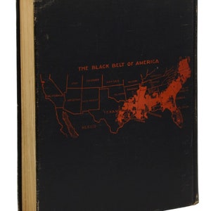 Puede incluir: Una cubierta de libro negra con un mapa rojo de los Estados Unidos. El mapa destaca el "Black Belt of America" con el texto "THE BLACK BELT OF AMERICA" en la parte superior.