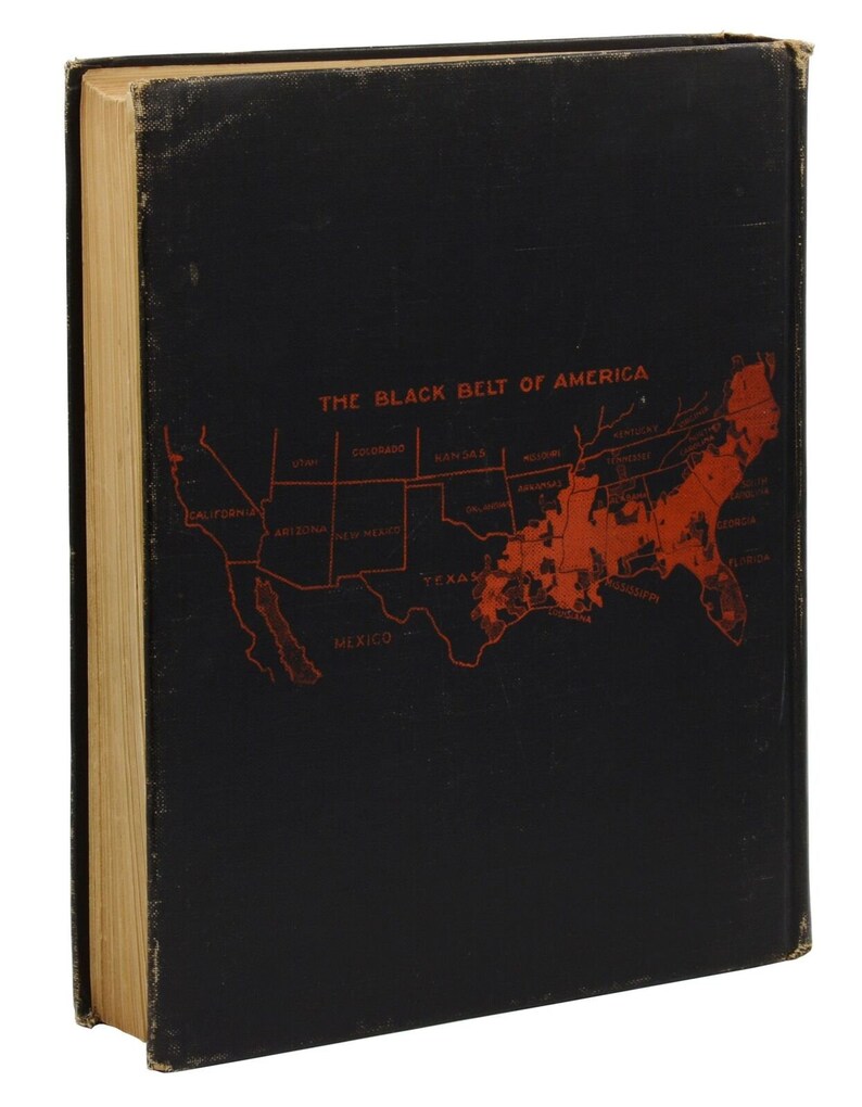 Puede incluir: Una cubierta de libro negra con un mapa rojo de los Estados Unidos. El mapa destaca el "Black Belt of America" con el texto "THE BLACK BELT OF AMERICA" en la parte superior.