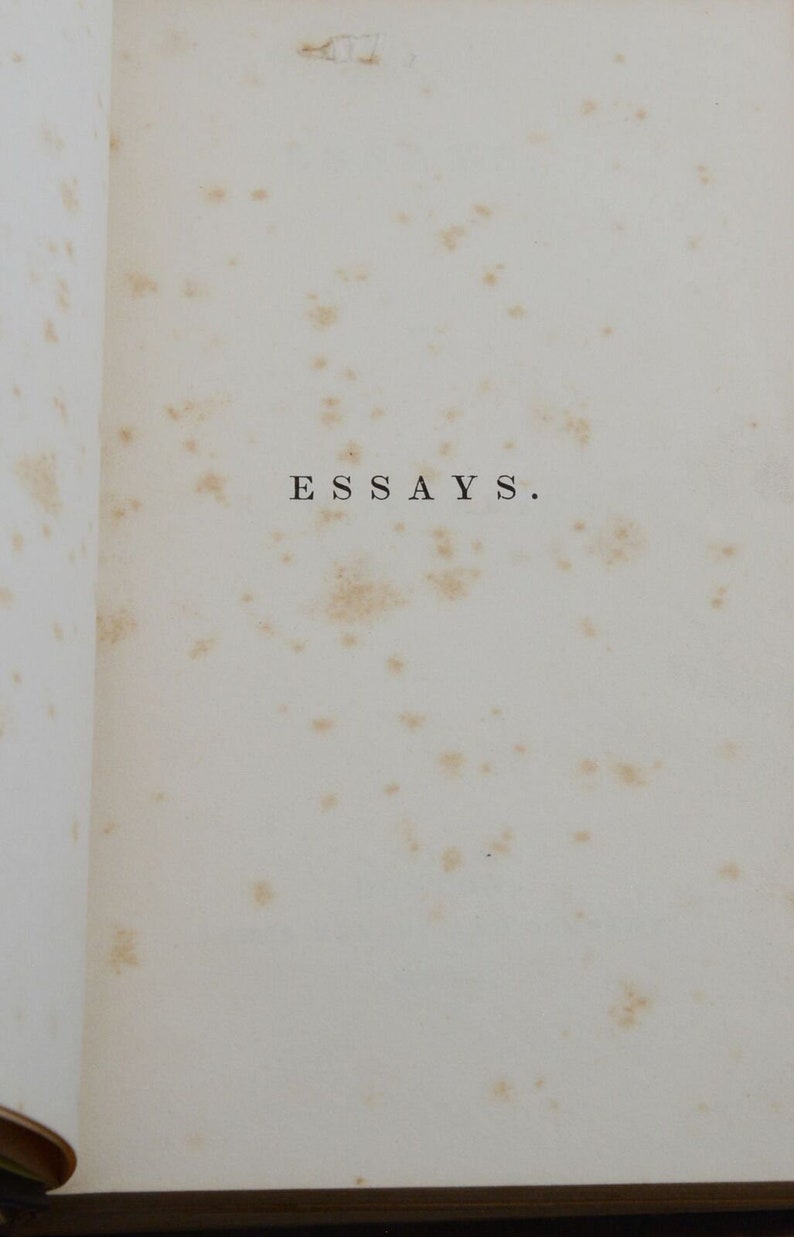 May include: A close-up of a page from a book with the word "ESSAYS" printed in black ink on a white background. The page is slightly yellowed and has several small brown spots.
