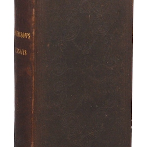 May include: A brown leather-bound book with gold lettering on the spine that reads "Emerson's Essays".