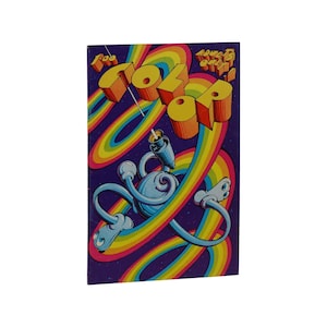 May include: A vintage comic book cover with a rainbow background and the title "The Color Of..." in yellow and orange letters. A blue cartoon character with a pen-like head is surrounded by rainbow swirls.