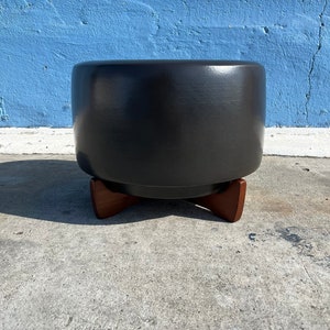 May include: A black ceramic stool with a round top and three wooden legs.