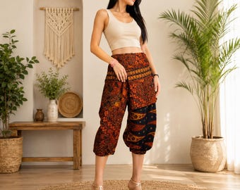 Puede incluir: Un top corto sin mangas de color beige combinado con pantalones holgados hasta la pantorrilla con un patrón complejo y multicolor en tonos naranja, rojo, marrón y negro. Los pantalones tienen una cintura ancha doblada y un dobladillo elástico.