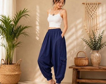 May include: A white sleeveless crop top paired with loose-fitting navy blue harem pants featuring an elastic waistband, cuffed ankles, and a side cargo pocket. The pants have a relaxed, baggy silhouette with deep side pockets and a solid color finish.