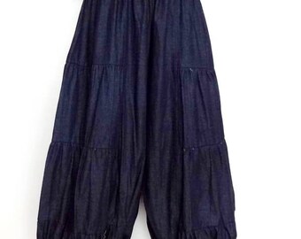 May include: Dark blue harem pants with a tiered design. The pants have an elastic waistband and a loose, flowing fit. The model is wearing the pants with sandals. The pants are made of a soft, lightweight fabric.