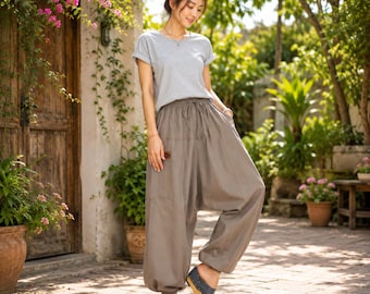 May include: A light grey short-sleeved t-shirt with a crew neckline paired with loose-fitting, taupe-coloured harem trousers featuring an elasticated drawstring waistband, side pockets, and gathered cuffs at the ankles, worn with dark grey open-toe sandals.