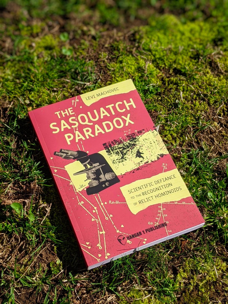 Op de afbeelding: Een rood boek met de titel "The Sasquatch Paradox" van Levi Machovec. De omslag toont een diagram en de tekst "Scientific Defiance to the Recognition of Relict Hominoids." Uitgegeven door Hangar 1 Publishing.
