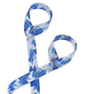 May include: Blue and white tie-dye wrist straps with metal accents. The straps are made of a soft, stretchy material and are designed to help improve grip and stability during exercise.