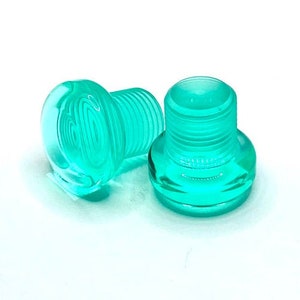 May include: Two turquoise plastic bottle stoppers with a threaded design.