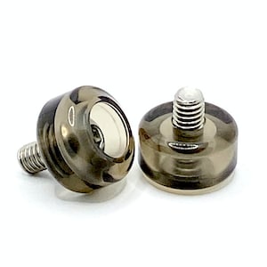 May include: Two clear, brown, plastic screw-in furniture feet with a silver metal screw.