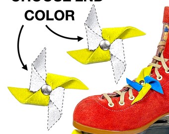 Puede incluir: Elige el 2º color. Un patín de ruedas rojo con molinetes amarillos, azules y blancos atados a los cordones. Los molinetes están hechos de fieltro y tienen una cuenta plateada en el centro.