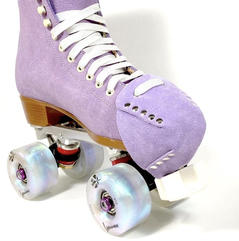 Może przedstawiać: Fioletowy rolkowy but z zamszu z białymi sznurowadłami i tęczowymi k&oacute;łkami. But ma stopę i białą płytę.