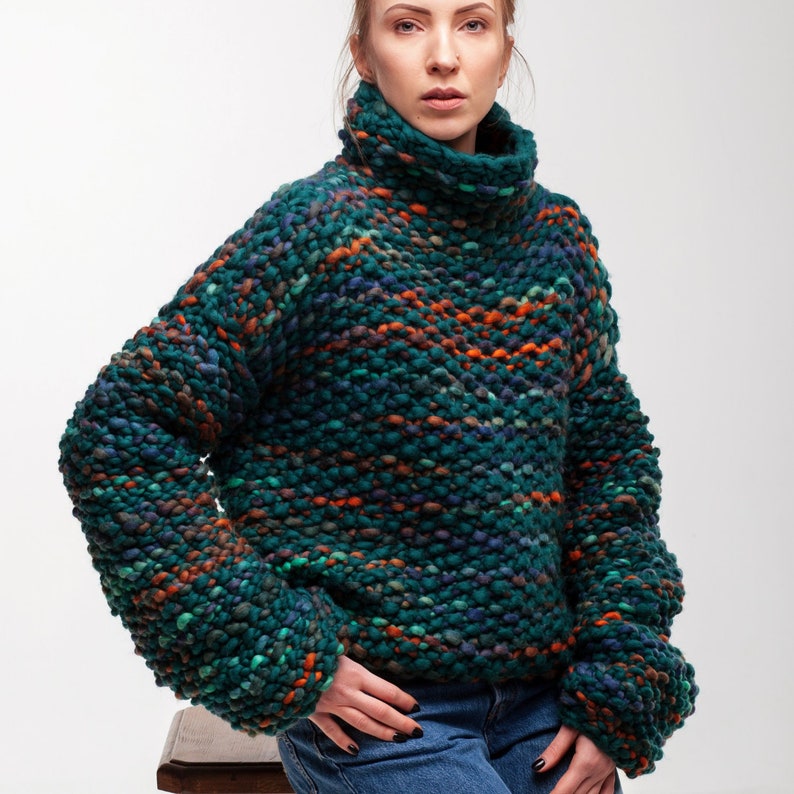 Oversized chunky knit sweater in green melange merino wool, shown on a model with soft cowl neck.