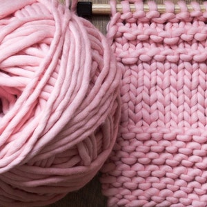 May include: A large ball of pink yarn and a knitted fabric swatch in the same color. The yarn is soft and fluffy, and the fabric is thick and textured.
