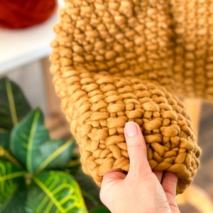 Close-up of mustard yellow chunky knit sweater sleeve and soft merino wool texture.