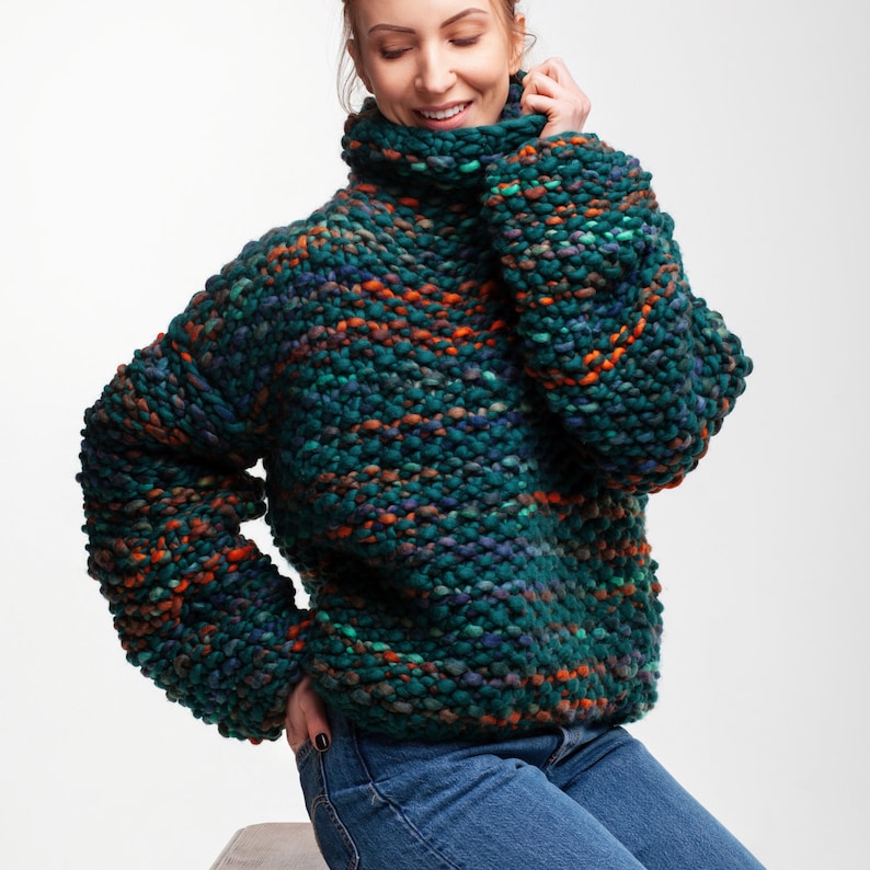 Oversized chunky knit sweater in green melange wool, styled with jeans and soft cowl neckline.