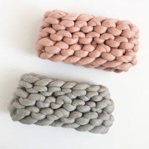 May include: Two chunky knit throw pillows, one in a light pink color and the other in a light gray color.
