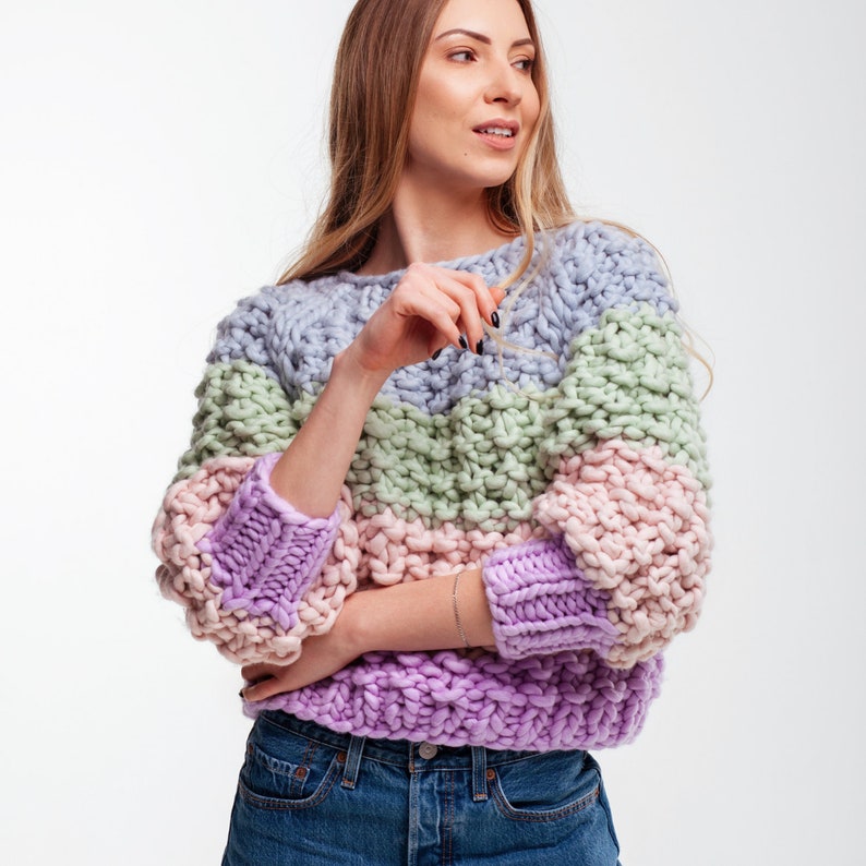 Three-quarter front view of the pastel chunky knit sweater with round neckline, color block stripes and loose three-quarter sleeves.