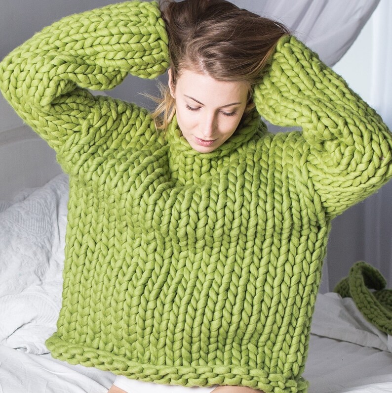 May include: A chunky knit sweater in a bright green color. The sweater is made of thick yarn and has a loose, oversized fit.