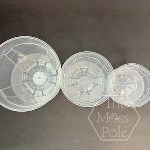 Peut inclure: Trois pots de fleurs en plastique transparent de diff&eacute;rentes tailles. Les pots ont un motif de grille au fond pour le drainage.