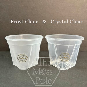 Peut inclure: Deux pots de plantes en plastique transparent, l'un avec une finition givr&eacute;e et l'autre avec une finition transparente. Les deux pots portent le logo "The Moss Pole" imprim&eacute; au fond.